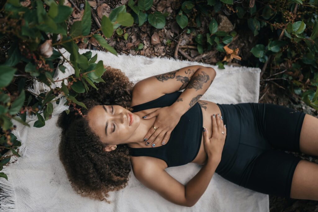 Woman Relaxing lying on the earth with one hand on belly and one on her heart 